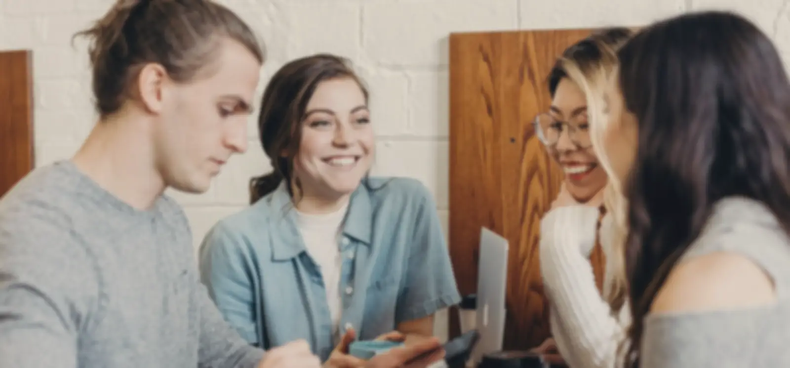 Young friends chatting and smiling round a café table