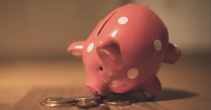 A red spotted piggy bank with a few coins