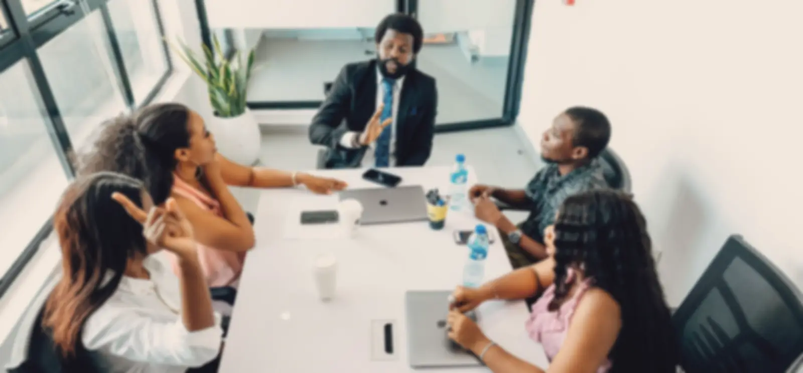 A small team talking round a meeting table with laptops and coffee
